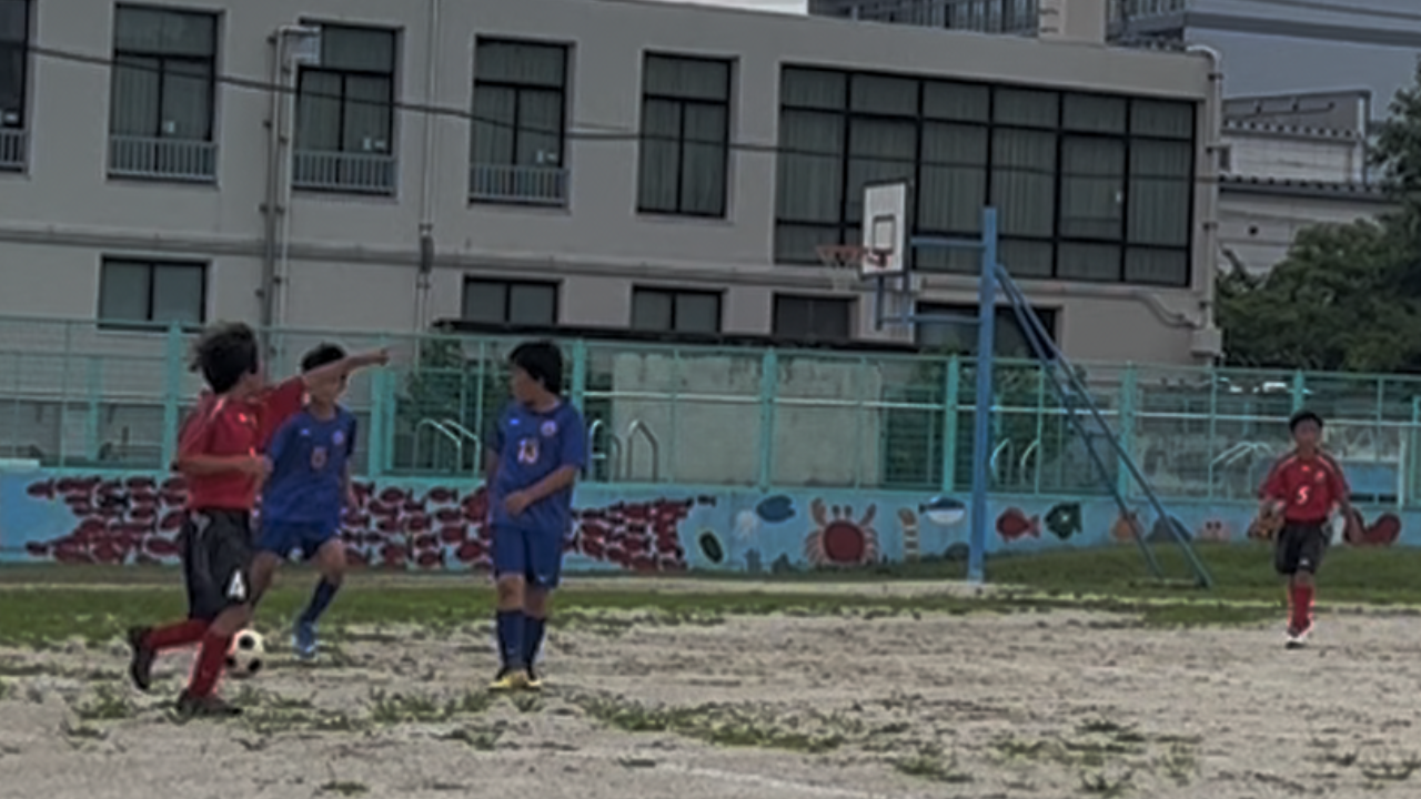 少年サッカーの試合で周りを見ながら指差しで味方に伝える選手